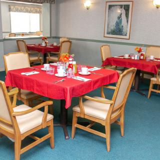 A cozy dining room with tables covered in red tablecloths and set for a meal.