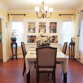 A cozy dining room with a table set for four, elegant chairs, and a chandelier overhead.
