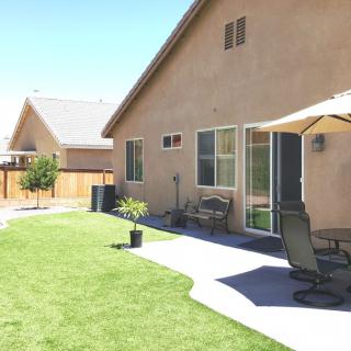 A sunny backyard with a nicely maintained lawn and outdoor seating area.