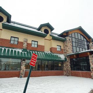 A modern commercial building covered in snow, featuring large windows and a distinctive architectural style.