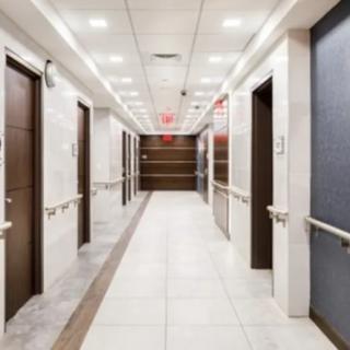 A modern hospital hallway with multiple doors and bright lighting.