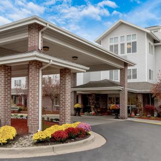 A large building with a covered entrance and surrounding landscaping.