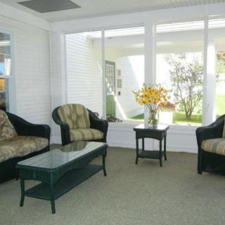 A cozy living room with sofas, a coffee table, and a floral arrangement by large windows.