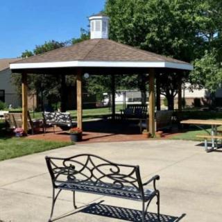 A gazebo with a nearby bench in a sunny outdoor setting.