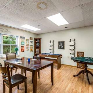 A cozy game room featuring a table, chairs, and various artworks on display.