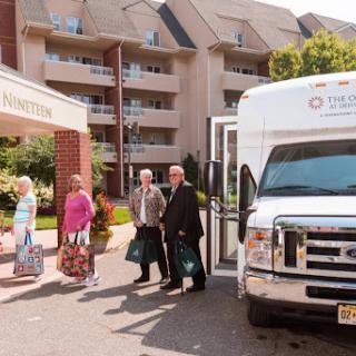 Guests arriving at a hotel with luggage, greeted by a shuttle bus.