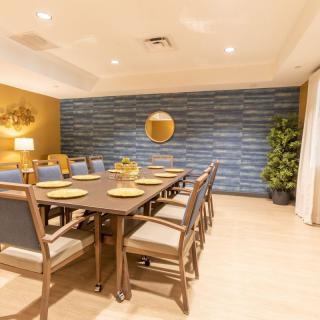 A modern dining room with a long table and chairs, featuring elegant lighting and decor.