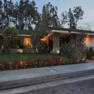 A cozy residential house with well-maintained landscaping and lit windows during the evening.