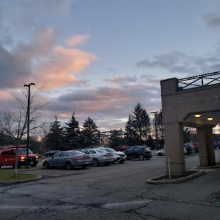 A tranquil evening scene in a parking lot, with colorful clouds framing the sunset.