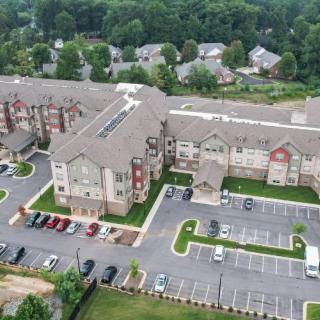 Aerial view of a residential building complex with adjacent parking lots and surrounding greenery.
