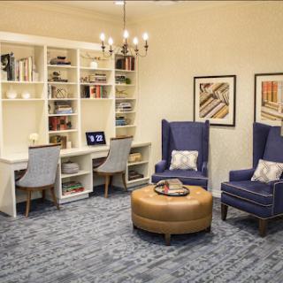 A cozy study area featuring comfortable chairs, a modern bookshelf, and an inviting ottoman.