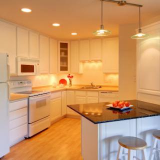 A modern kitchen featuring white cabinetry, wooden flooring, and an island countertop with decorative items.