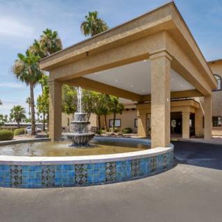 Hotel entrance with a decorative fountain and palm trees.