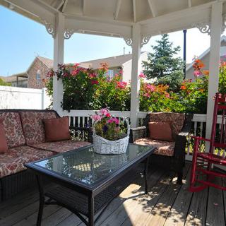 A cozy gazebo with comfortable seating and vibrant flowers, perfect for outdoor relaxation.