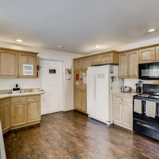 A modern kitchen with wooden cabinets, equipped with appliances and a hardwood floor.