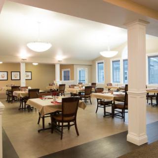 A spacious and well-lit dining room with neatly arranged tables and chairs.