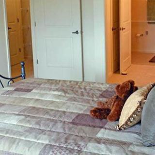 Cozy bedroom with a neatly made bed and a teddy bear.