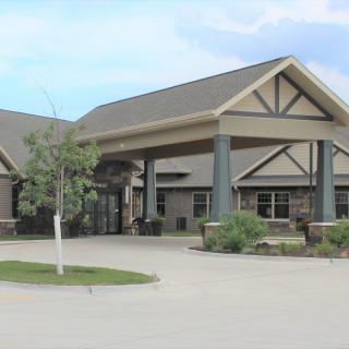 A building with a covered entrance and landscaping in front.