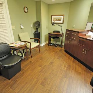 A small waiting room with chairs, a desk, and wooden flooring.