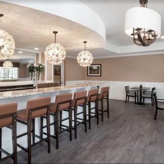 A modern dining area featuring a bar counter with high chairs and elegant pendant lighting.