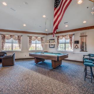 A billiards room featuring a pool table, seating, and large windows with an American flag hanging from the ceiling.