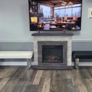 A modern waiting room with a cozy fireplace and television.