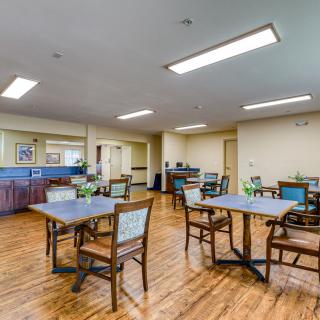 A well-lit dining area with tables and chairs arranged neatly on a wooden floor.