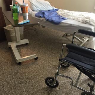 A hospital patient room featuring a bed and a wheelchair.