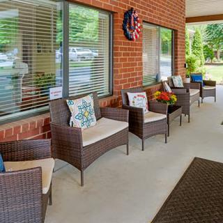 A cozy patio area with wicker chairs and colorful cushions against a brick wall.