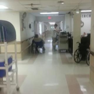 A hallway in a hospital with medical equipment and a person in a wheelchair.