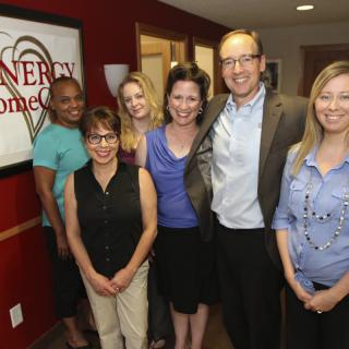 A group of six people posing together in an office setting.