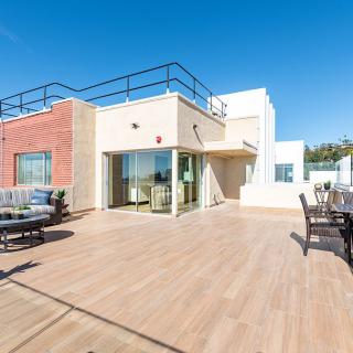 A spacious rooftop terrace with outdoor seating under a clear blue sky.