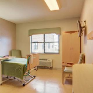 A clean and organized hospital room with a patient bed and seating area.