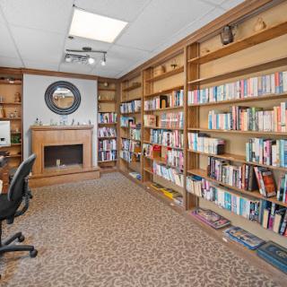 A cozy home library featuring extensive bookshelves, a fireplace, and a comfortable reading nook.