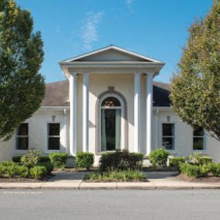 A charming residential building featuring classic architectural elements and well-maintained landscaping.