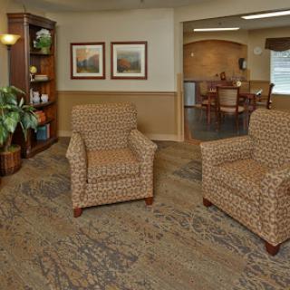 A cozy sitting area featuring patterned armchairs, a bookshelf, and decorative art.