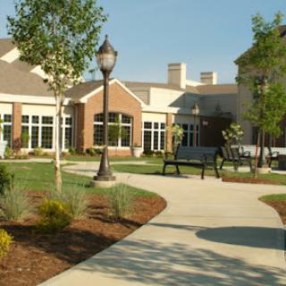 A serene outdoor space featuring a pathway, lush landscaping, and modern architecture.