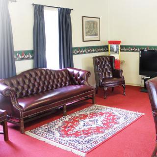 A traditional living room with a leather sofa, matching chairs, and a decorative rug.
