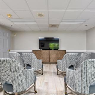 A small conference room with arranged chairs facing a television.