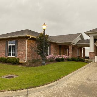 A stylish single-story brick house with a beautifully landscaped yard and outdoor lighting.