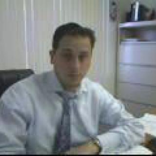 A person sitting at a desk in an office wearing business attire.