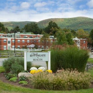 A scenic view of a residential building surrounded by lush gardens and mountains in the background.