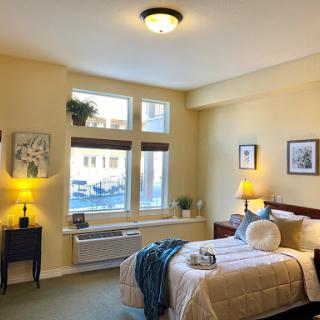 A cozy bedroom filled with natural light, featuring a neatly made bed and tasteful decor.