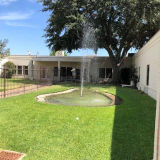 A serene outdoor space featuring a fountain surrounded by lush green grass and trees.