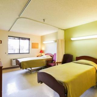 A hospital room with two beds and a window letting in natural light.