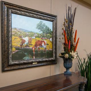 A serene landscape painting alongside a vibrant floral arrangement, enhancing the interior decor.