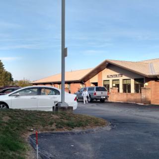 A view of a building with vehicles parked in front during a clear day.