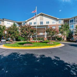 A well-maintained residential building with a circular driveway and landscaped gardens on a sunny day.