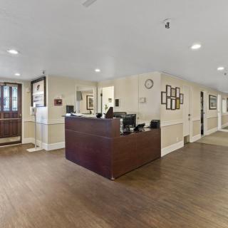 A spacious reception area with a wooden desk and floors, featuring office equipment and wall decor.