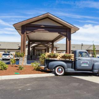 A vintage truck parked in front of a building entrance with landscaped surroundings.